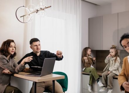 Family discussing real estate purchase inside home with agent and children present.