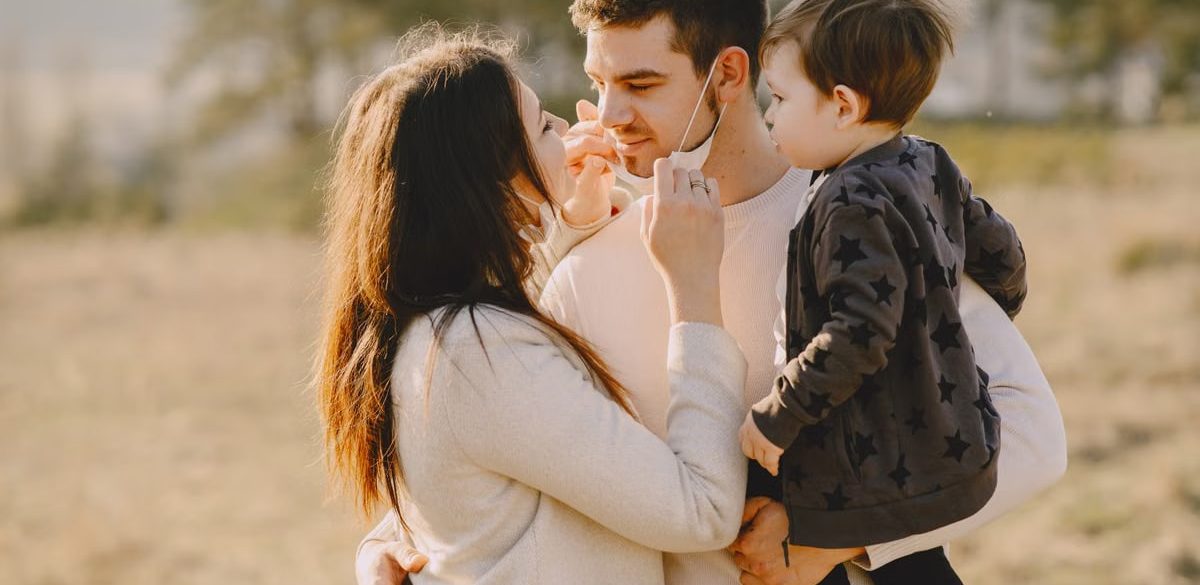 Family sharing affectionate moments outdoors with parents and child enjoying the sunny day.