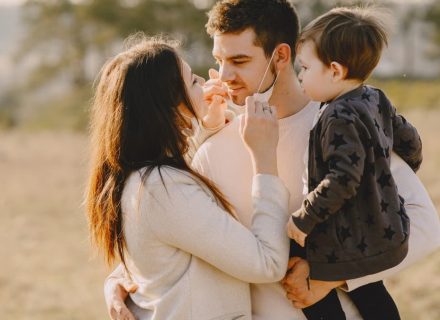 Family sharing affectionate moments outdoors with parents and child enjoying the sunny day.