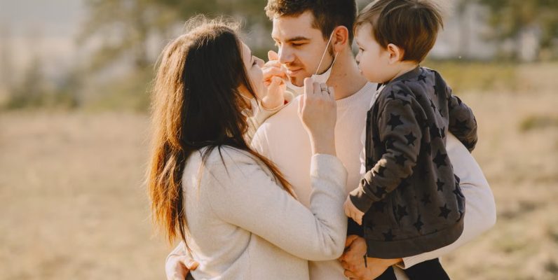 Family sharing affectionate moments outdoors with parents and child enjoying the sunny day.